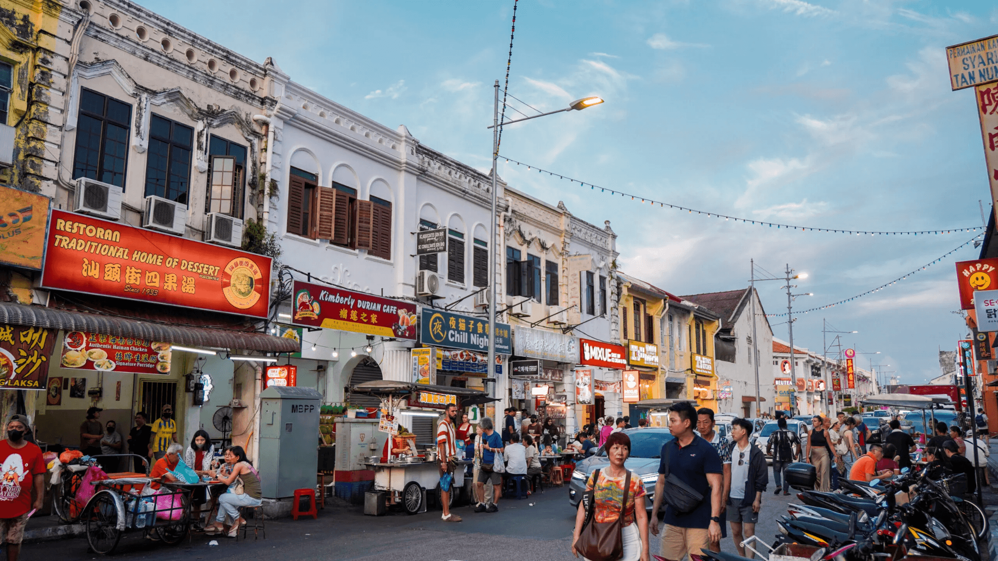 Food stalls, heritage shophouses and pedestrians along a lively Penang street